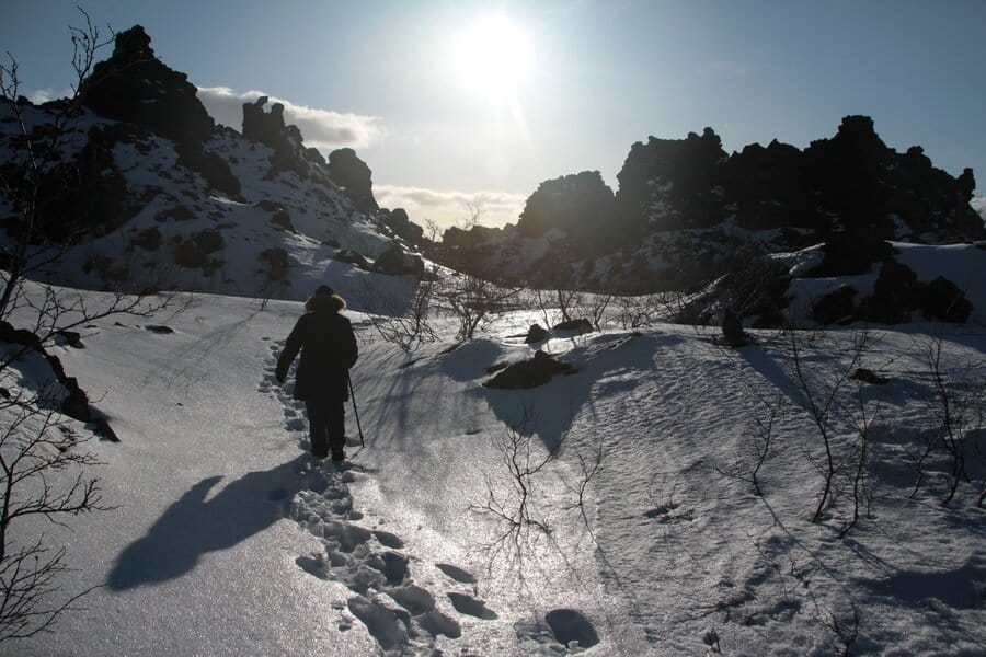 A person walking through snow and rocks
