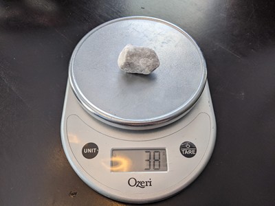 A landscaping rock on a scale showing that it weighs 38 grams